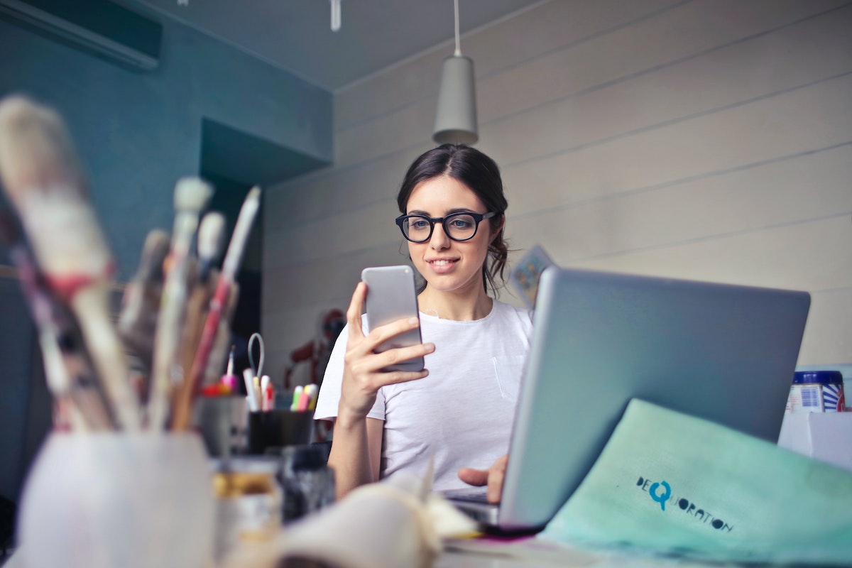A woman wearing glasses looks at her phone