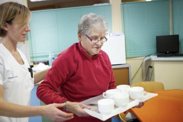 Therapist assisting a woman with a tray